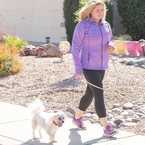 Woman walking a toy poodle on a loose leash after completing leash reactivity training with FurBabies & Friends.